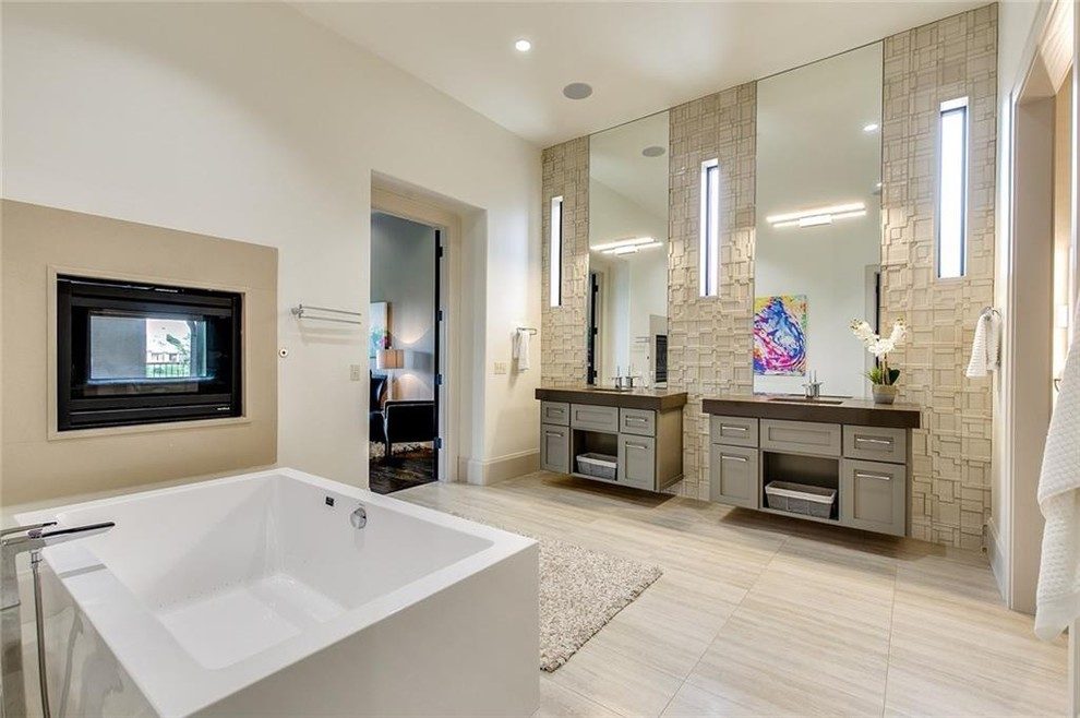 Contemporary master bathroom with floating grey vanities and a freestanding tub