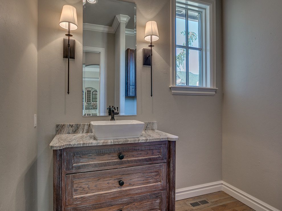 Powder bath with a dark walnut furniture-style vanity, a stone top and sconce lighting