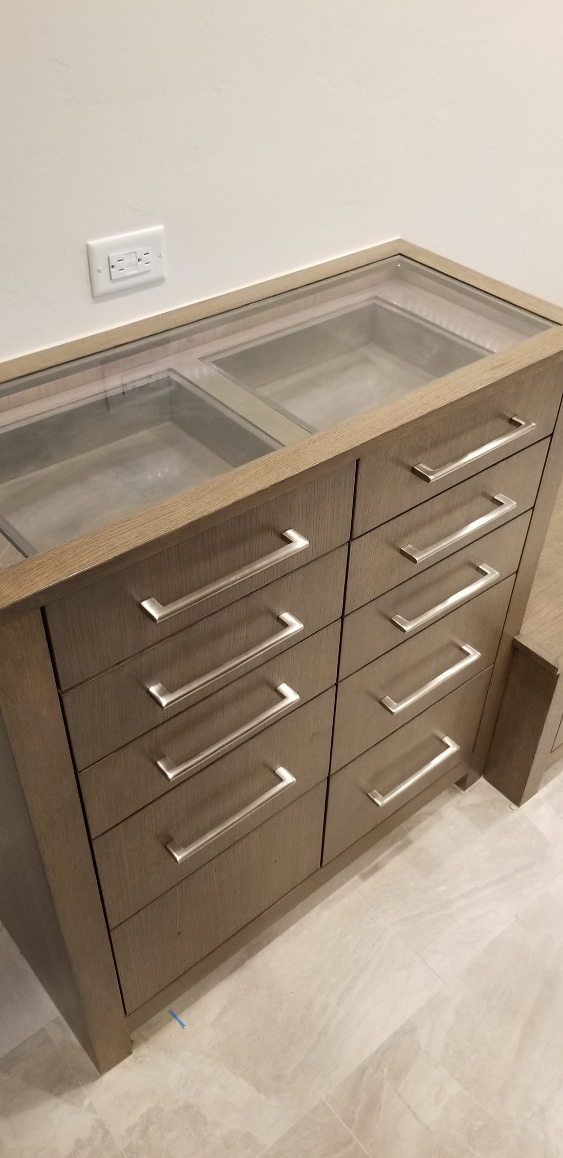 Walk-in dressing room with stained cabinetry and a glass-topped display island