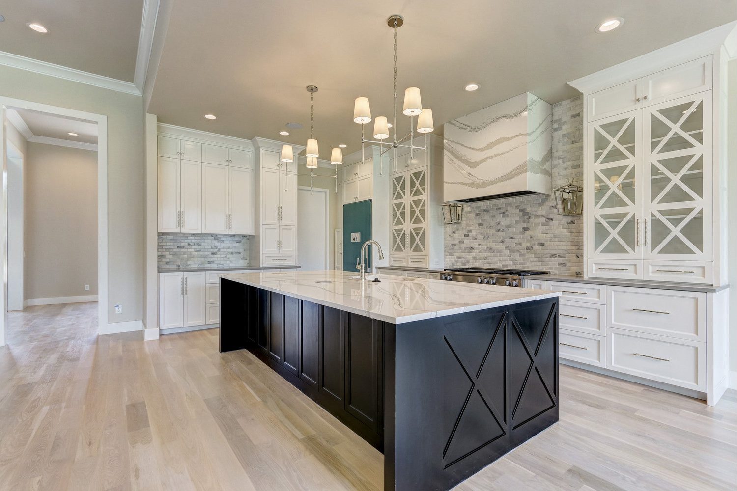 Transitional kitchen with white shaker cabinetry, a black x-panel island and a quartz-wrapped range hood